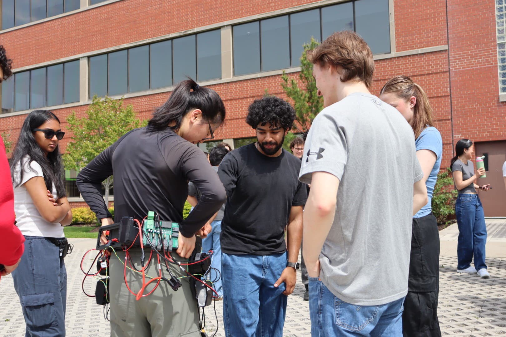 McMaster team members checking the exoskeleton outdoors before an ACE 2026 event.