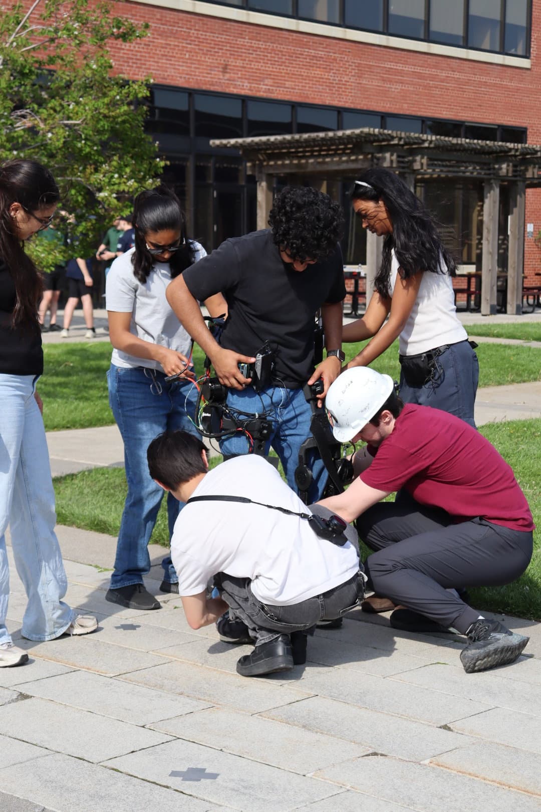 Team members kneeling beside the pilot to adjust the exoskeleton before a run.