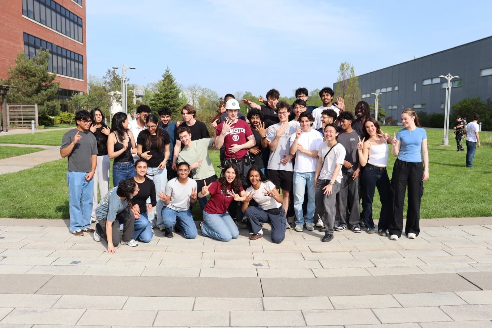 McMaster Exoskeleton students gathered with their pilot and suit outside the engineering building at ACE 2026.